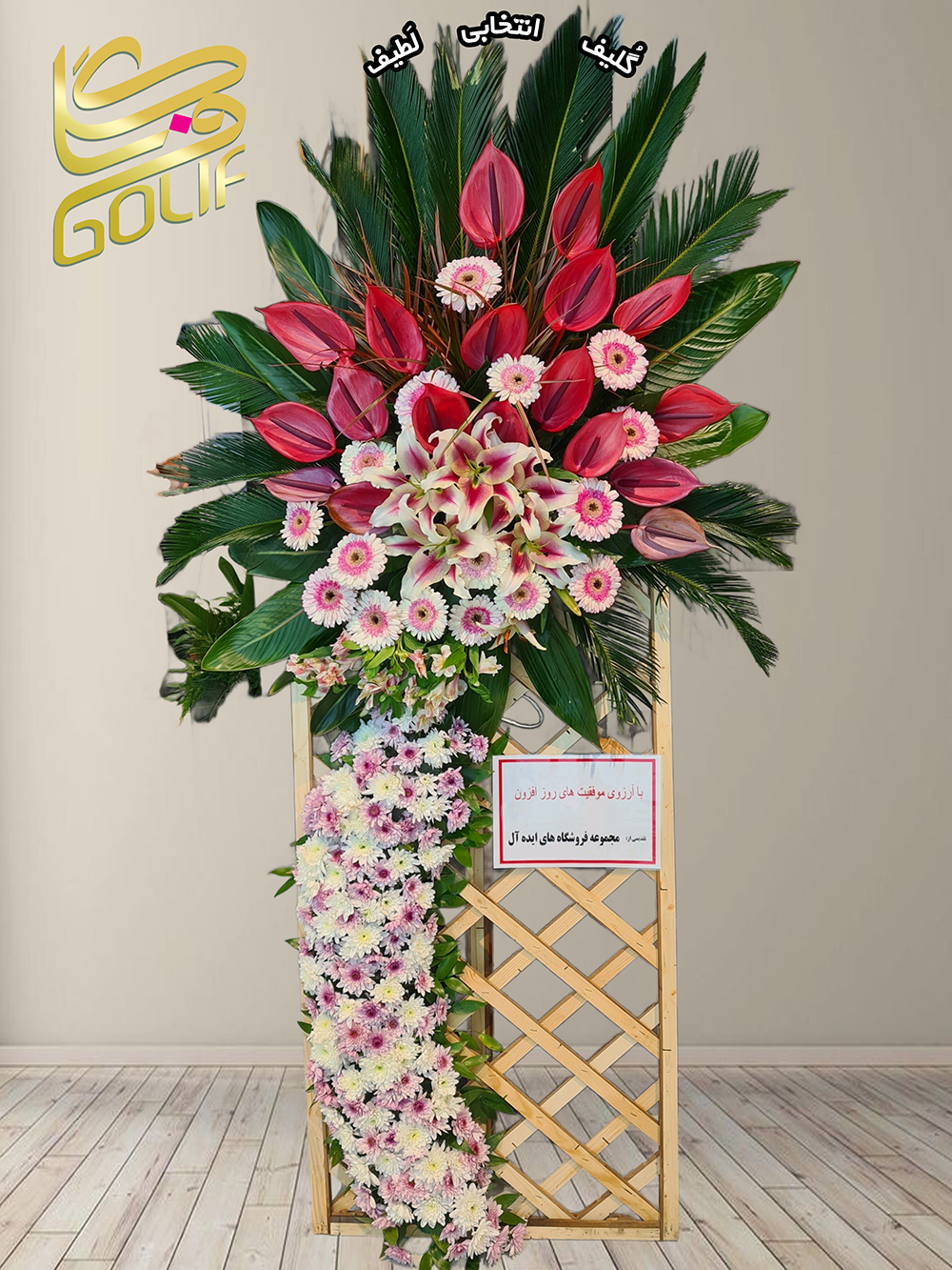 تاج گل تبریک شبکه‌ای شاد (آنتوریوم، ژربرا، لیلیوم) گل‌های اصلی و غالب این تاج گل شامل موارد زیر هستند: آنتوریوم قرمز: این گل‌ها در قسمت‌های مختلف تاج به‌ویژه در مرکزیت طراحی برجسته و خیره‌کننده هستند. ژربرا صورتی: با زیبایی خاصی در اطراف تاج گل خودنمایی می‌کند. لیلیوم سفید: این گل‌ها نیز در بخش‌های گوناگون ترکیب حضور دارند و جلوه‌ای باشکوه به تاج گل بخشیده‌اند. این طراحی در کنار برگ‌های سبز و جزئیات دیگر نمایانگر هنری فاخر و مناسب برای مناسبت‌های خاص است. تاج گل افتتاحیه، تاج گل نمایشگاهی، تاج گل عقد و عروسی سفارش آنلاین تاج گل سفارش آنلاین گل